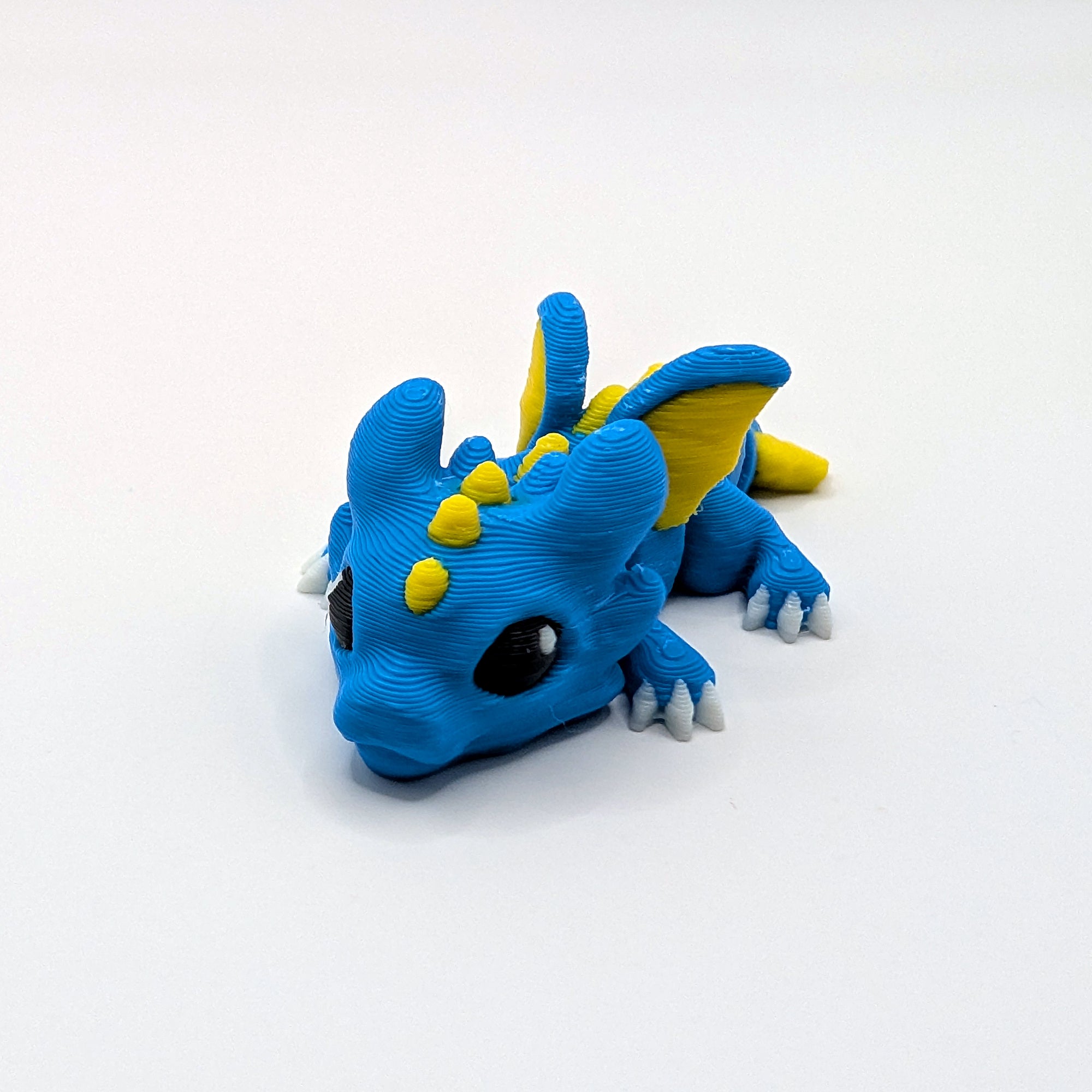 Blue and yellow Dragon Hatchling articulated 3D-printed fidget companion, three-quarter view