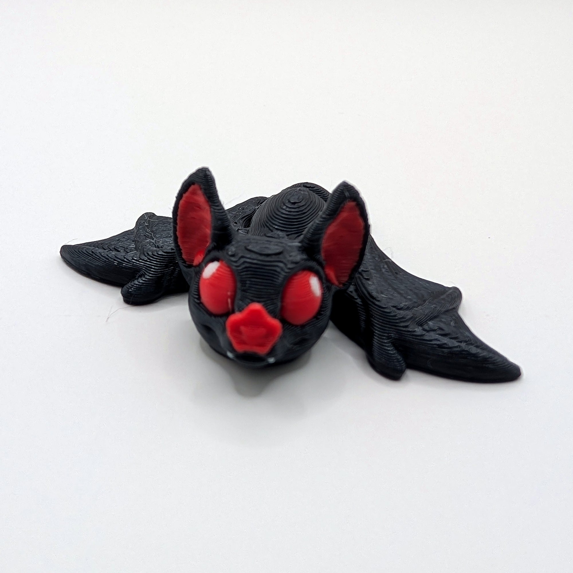 Black bat Hatchling articulated 3D-printed fidget companion with wings open